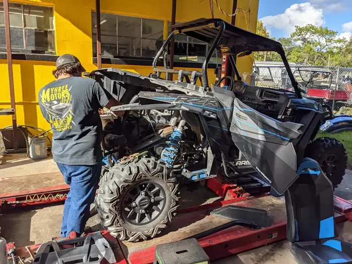 A TMT Offroad technician servicing a Polaris side-by-side on the lift in Williston, FL